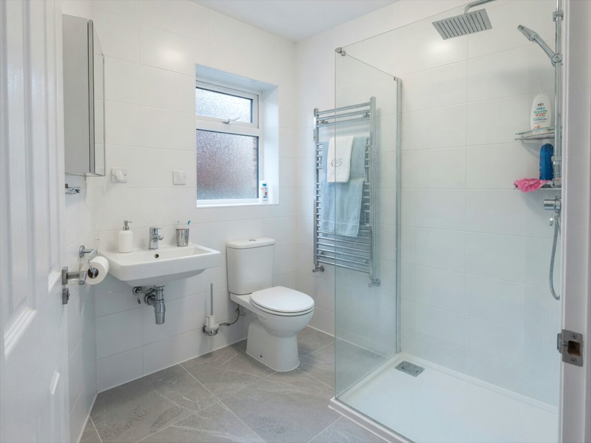 Refurbished family bathroom with walk-in glass shower and grey floor tiles